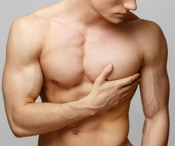 Muž s gynekomastií dotýká zvětšeného prsu.