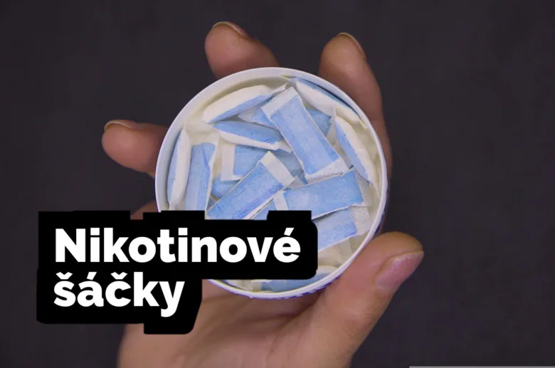 Ruka drží otevřenou nádobu s modrými nikotinovými sáčky.