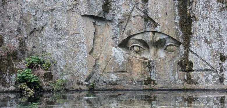 Výřez tváře s očima v skále nad vodou u Úst pravdy.