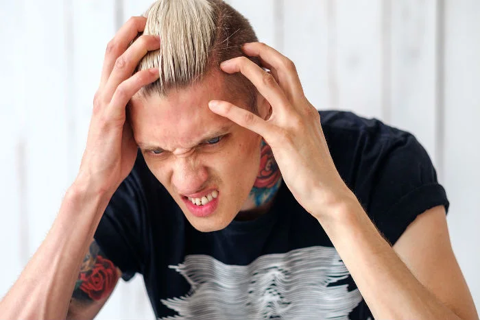 Muž drží hlavu v bolestech hlavy.