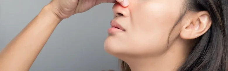 Žena dotýká nosu v profilu kvůli možným polypům.