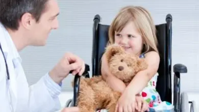 Lékař hovoří s dívkou v invalidním vozíku držícího medvěda.
