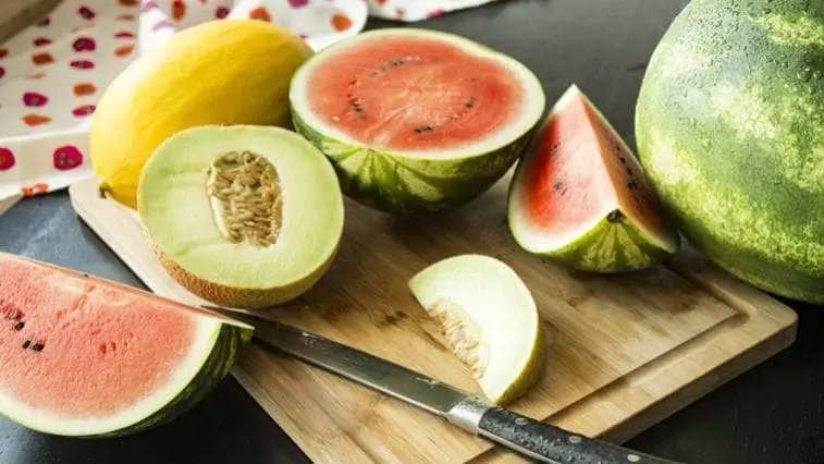 Žlutý meloun, vodnímelóna a nůž na dřevěném prknu.