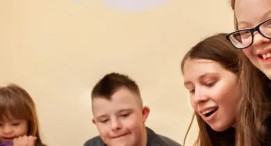 Skupina šťastných lidí se dívá dolů na něco mimo záběr.