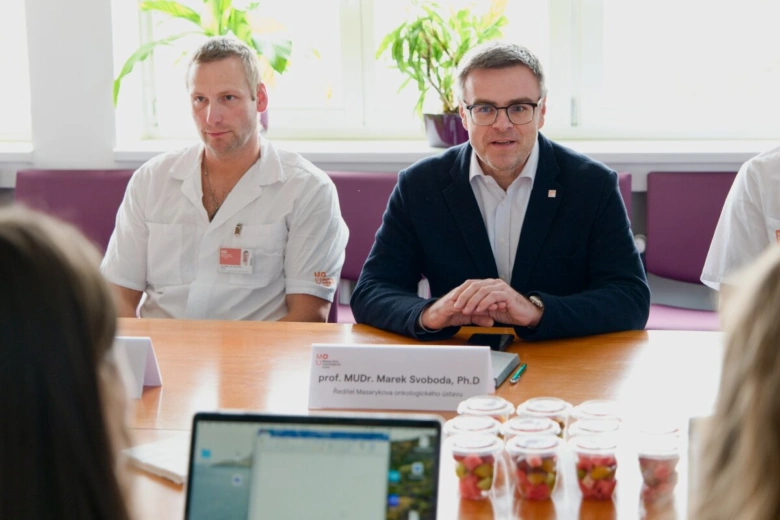 Dva lékaři sedí za stolem během schůzky o léčbě nádoru slinivky.