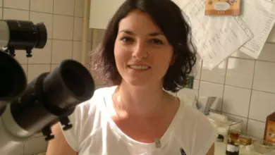 Žena v bílé košili s identifikačním štítkem u oftalmologického vybavení.