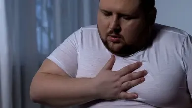 Muž drží ruku na hrudi v bolesti.