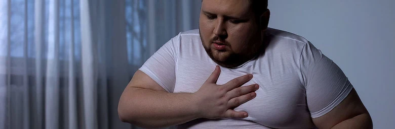Muž drží ruku na hrudi v bolesti.