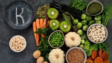 Různé potraviny bohaté na vitamín K jako brokolice, mrkev a špenát.