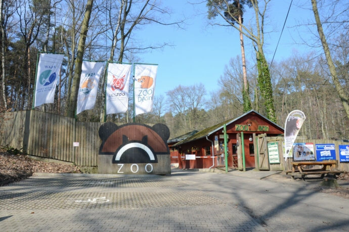 Vstup do zoologické zahrady s vlajkami a medvědí logem.