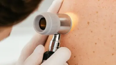 Dermatolog zkoumá skvrny na kůži pomocí derooskopu.