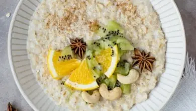 Mísa s ovesnou kaší ozdobená kiwi, pomerančem, mandlemi a hvězdicovitým anýzem.