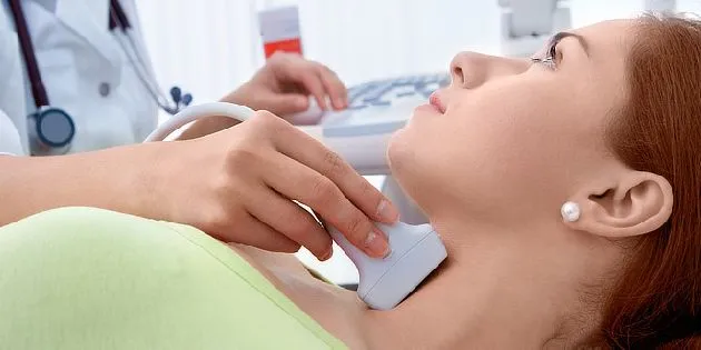 Lékař provádí ultrazvukovou vyšetření štítné žlázy pacientovi.