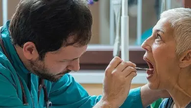Lékař vyšetřuje hrdlo pacienta pomocí nástroje.