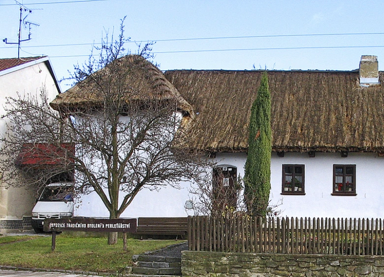 Tradiční došková střecha na venkovském domě s bílými zdmi.