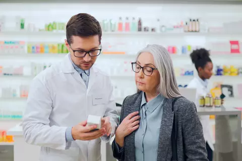 Farmaceut porovnává léky s pacientem v drogerii.