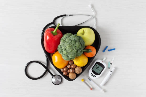 Srdcovitý talíř s ovocem, zeleninou, glukometrem a jehlicemi pro diabetiky.