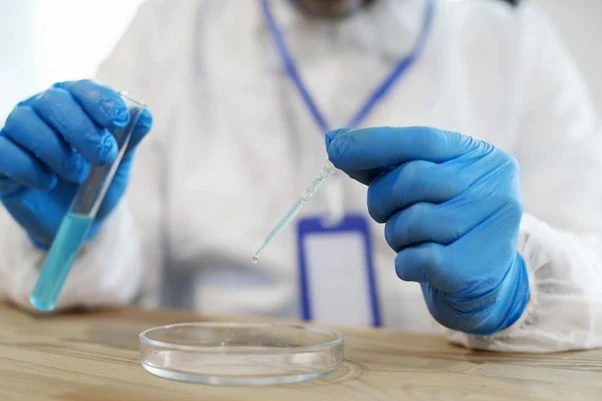 Vědec v laboratoři s pipetou a zkumavkou pro analýzu vody.