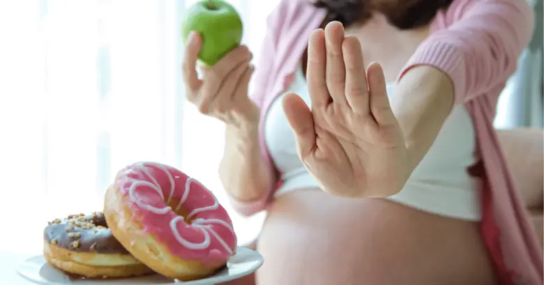 Těhotná žena odmítá sladkosti ve prospěch jablka.