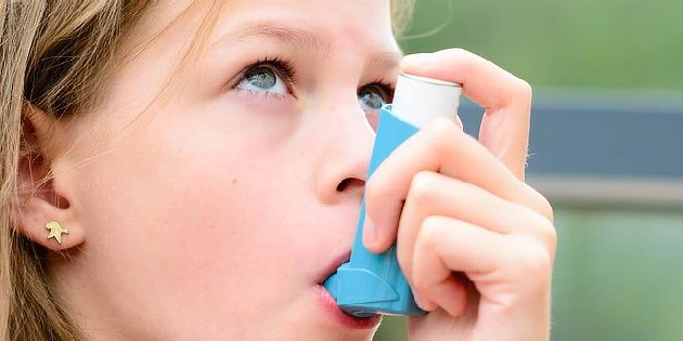 Dívka používá inhalátor pro astma.