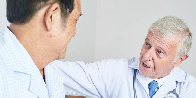 Lékař vysvětluje staršímu muži příznaky zvětšené prostaty.