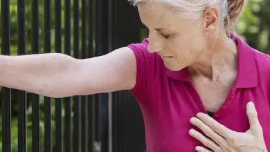 Žena se drží za hrudník v bolesti při angině pectoris.