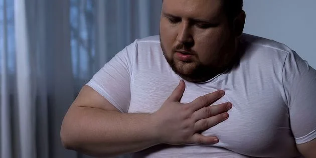 Muž drží ruku na hrudi v bolesti.