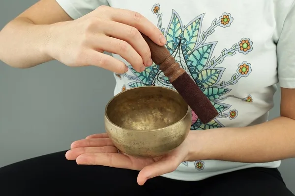Ruce drží tibetskou zvonku pro harmonizaci čakr.