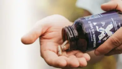 Ruce s lahvičkou vitamínu K2 MK-7 a tobolky v dlani.