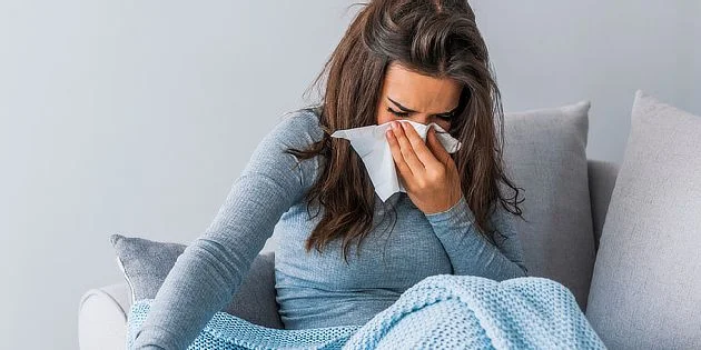 Žena sedí na gauči s chřipkou a používá vložku.