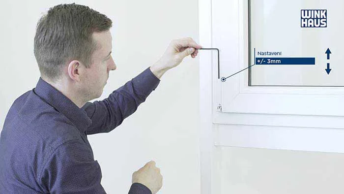 Muž nastavuje plastové okno pomocí speciálního klíče.