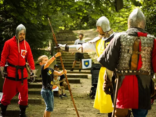 Dětská hra s rytíři v kostýmech na venkovní akci.