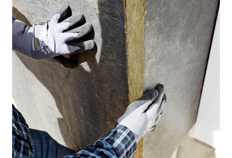 Ruční instalace tepelné izolace na potrubí v průmyslovém prostředí.